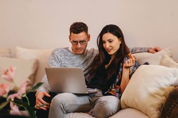 Couple sitting on a couch while looking at a laptop computer together at Addison Ranch Apartments, Petaluma, CA, 94954